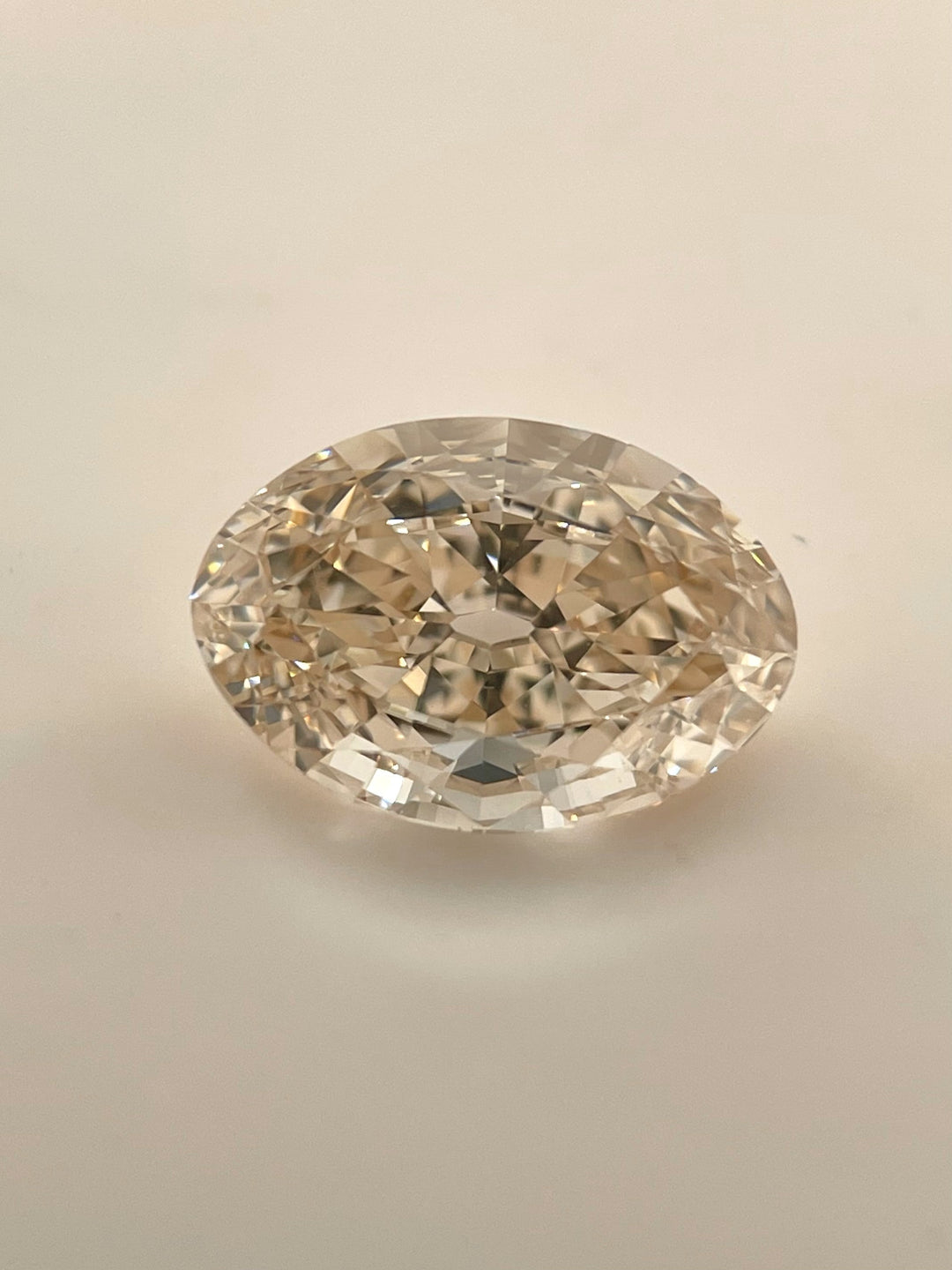 A close-up of a 3.01-carat fancy light brown champagne diamond in an antique old mine moval cut, resting on a clean white background, highlighting its internal flawless clarity and symmetrical brilliance.