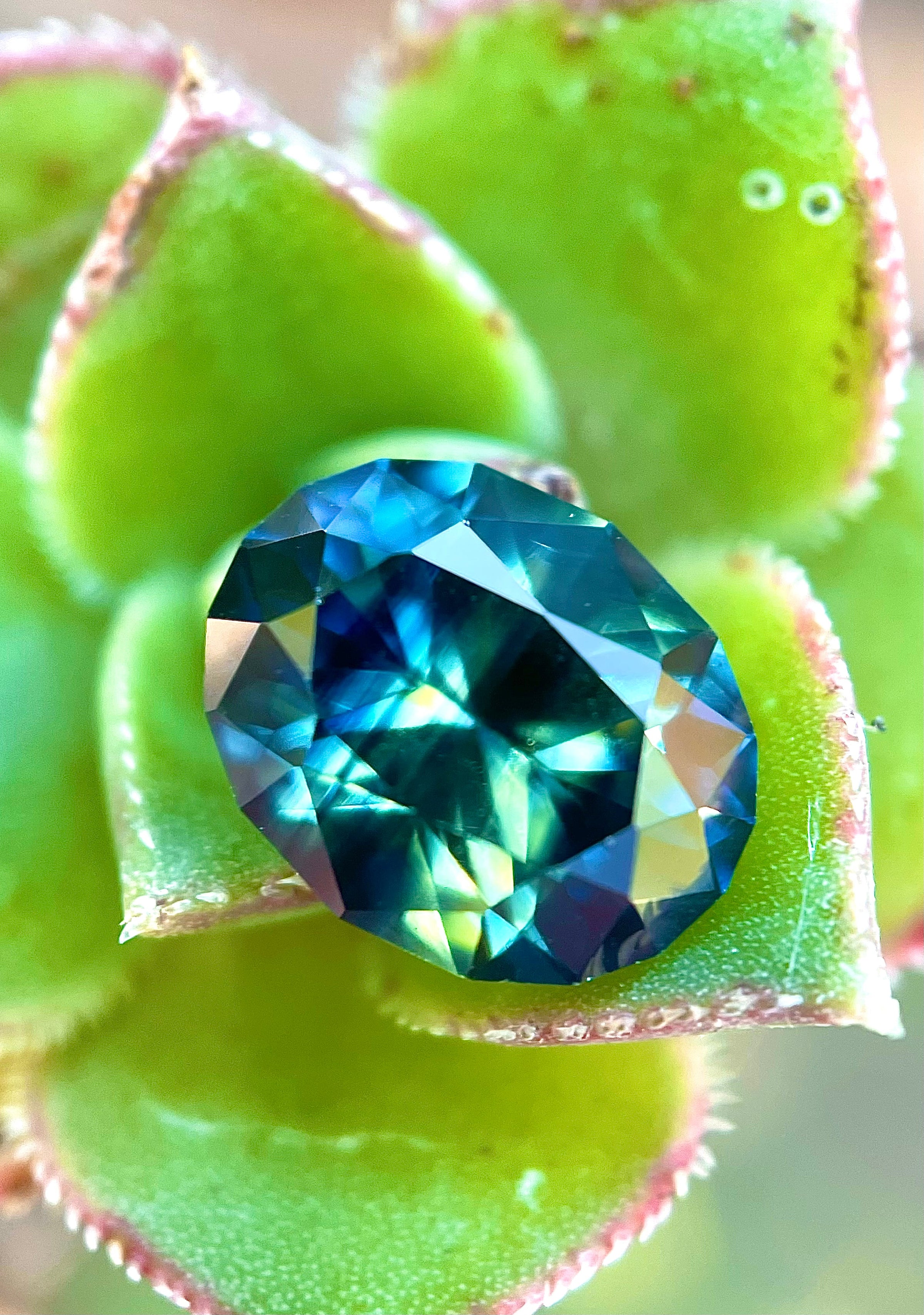 Untreated Nigerian sapphire – teal and peacock hues, ethically sourced gemstone photographed for Caleb B. Quashen International.