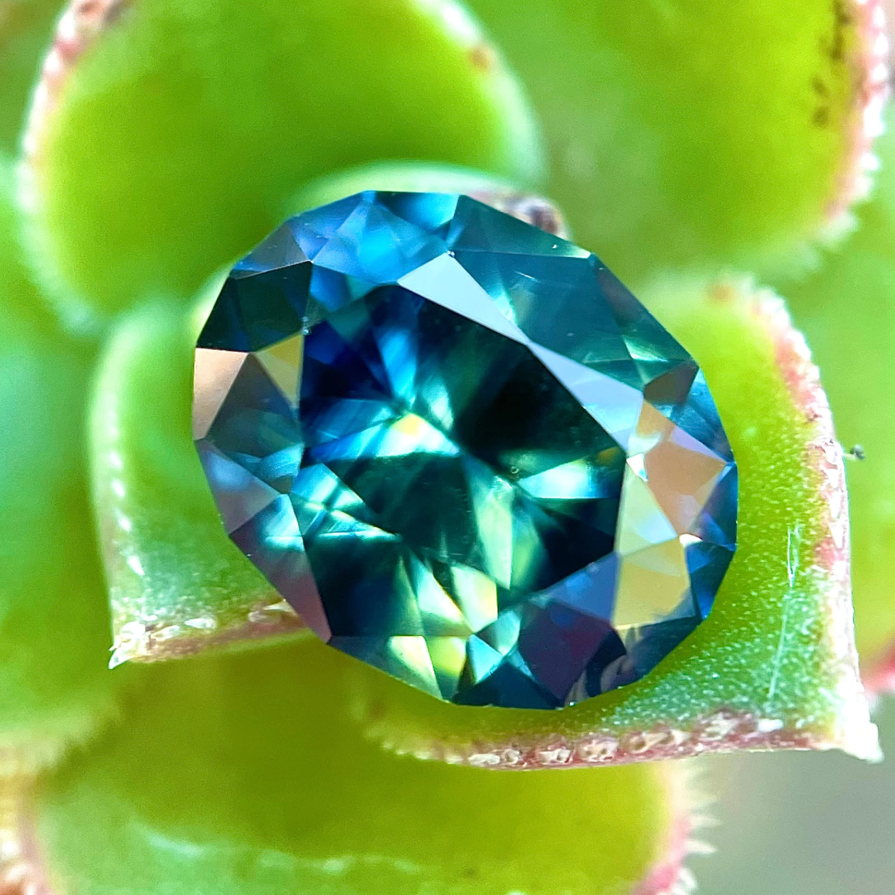 Untreated Nigerian sapphire – teal and peacock hues, ethically sourced gemstone photographed for Caleb B. Quashen International.