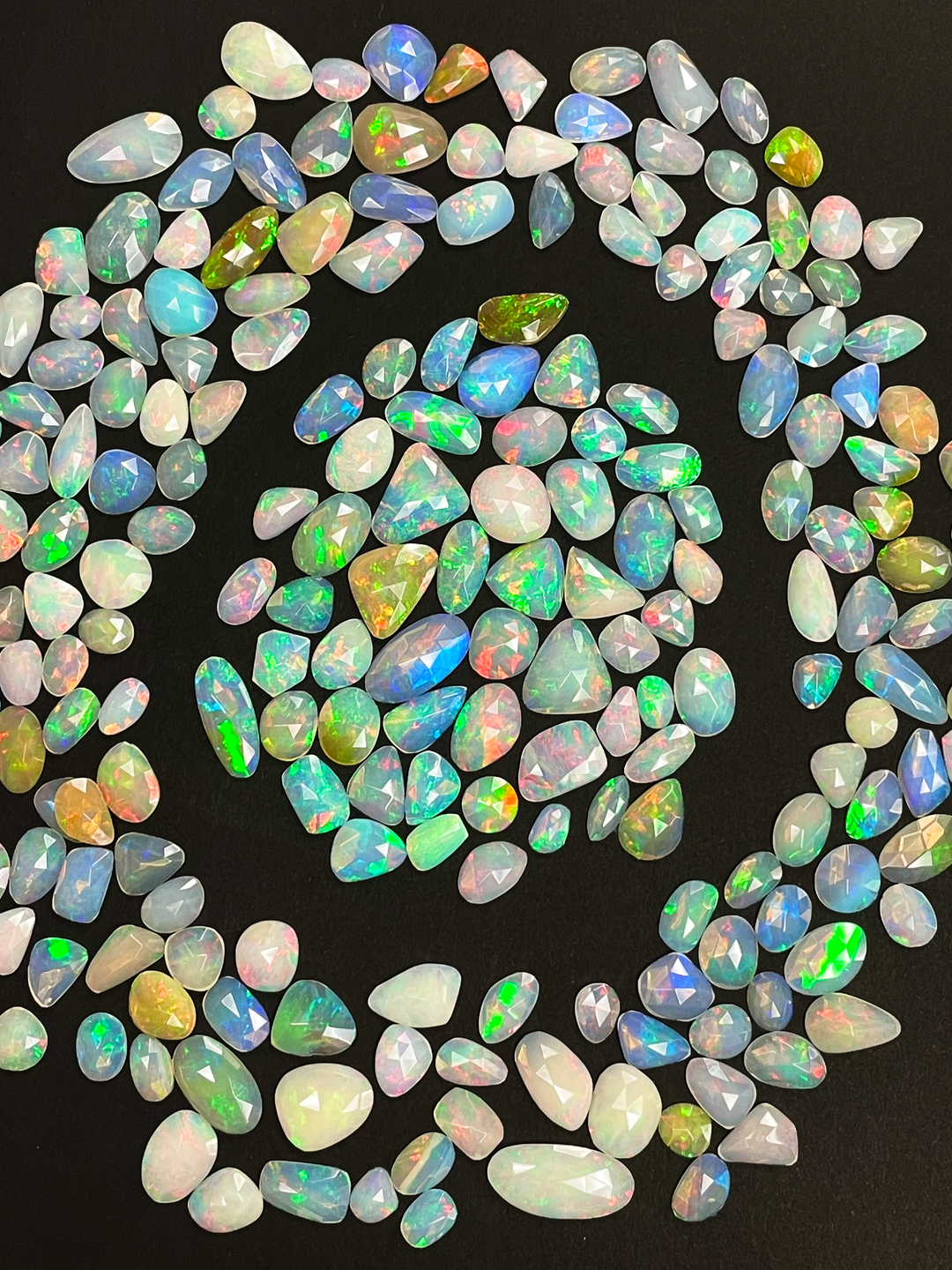 Natural opal gemstones shimmering with iridescent hues and watercolor fire — CBQ International.