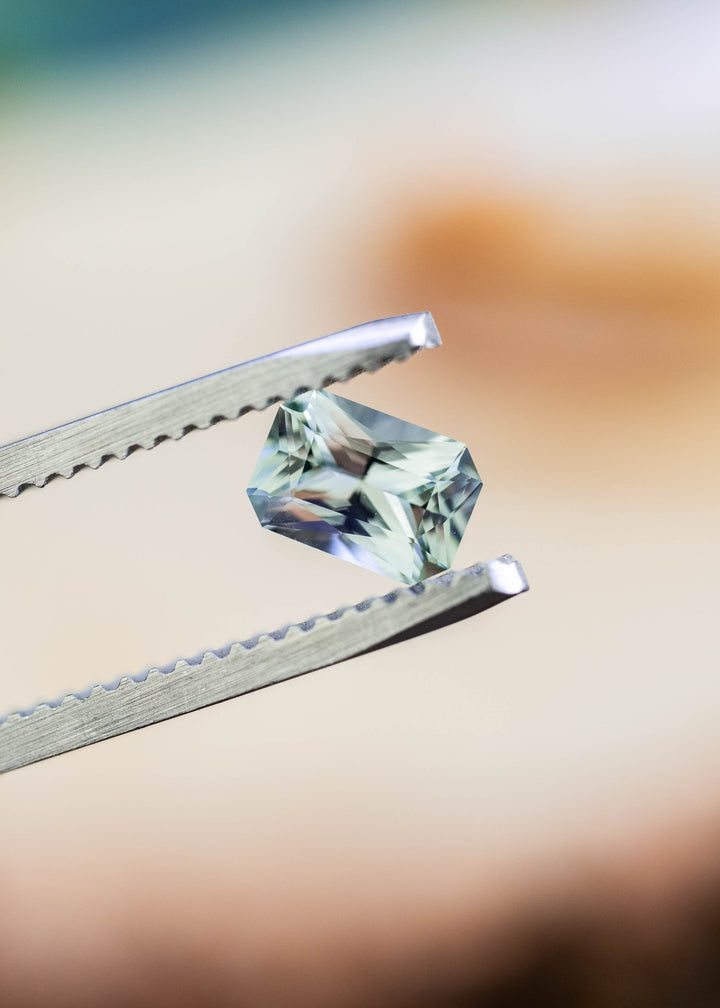 Close-up of an untreated 0.695 carat Montana sapphire showing its precision radiant cut and delicate seafoam green brilliance.