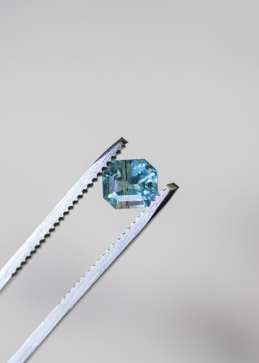Close-up of a 0.88 carat untreated Nigerian aquamarine showing crisp octagonal step facets and rich blue-green color.