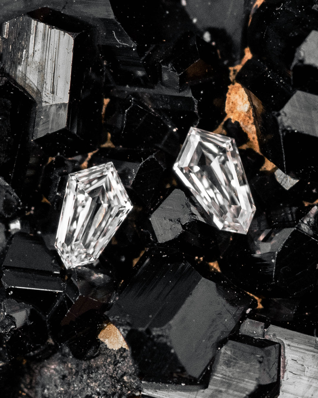 Pair of 0.10ct F-G color VVS clarity kite step cut diamonds from South Africa displayed on a black crystal matrix, showing precision faceting, sharp symmetry, and exceptional brilliance in a macro gemstone photography scene.