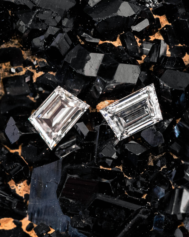 0.28 carat F–G color VVS clarity Trapezoid step cut diamond pair resting on a black crystal mineral matrix, highlighting the geometric faceting, brilliance, and matched shape of two natural untreated South African diamonds.