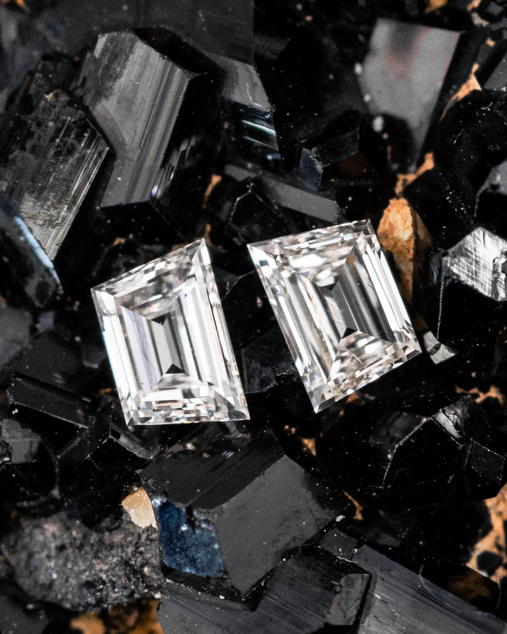 0.29 carat G–H color VVS clarity trapezoid step cut diamond pair resting on a black crystal mineral matrix, highlighting the geometric step facets, crisp edges, and sparkle of natural untreated South African diamonds.