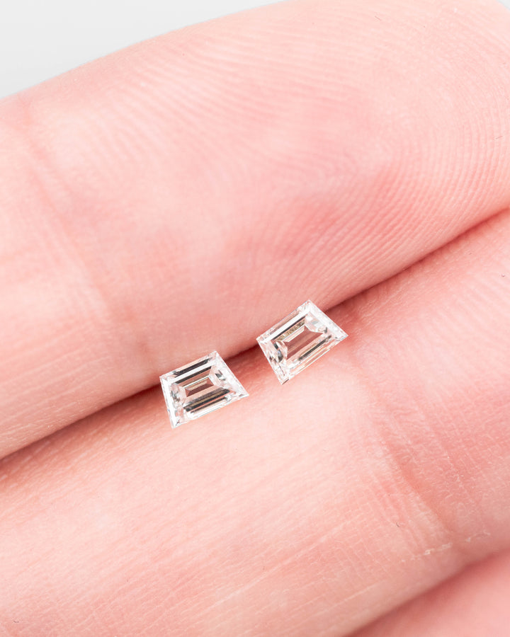 0.30 carat F-G color VVS clarity Trapezoid step cut diamonds from South Africa resting on a black crystal mineral matrix, highlighting the precision step-cut faceting and natural sparkle of the untreated matched pair.
