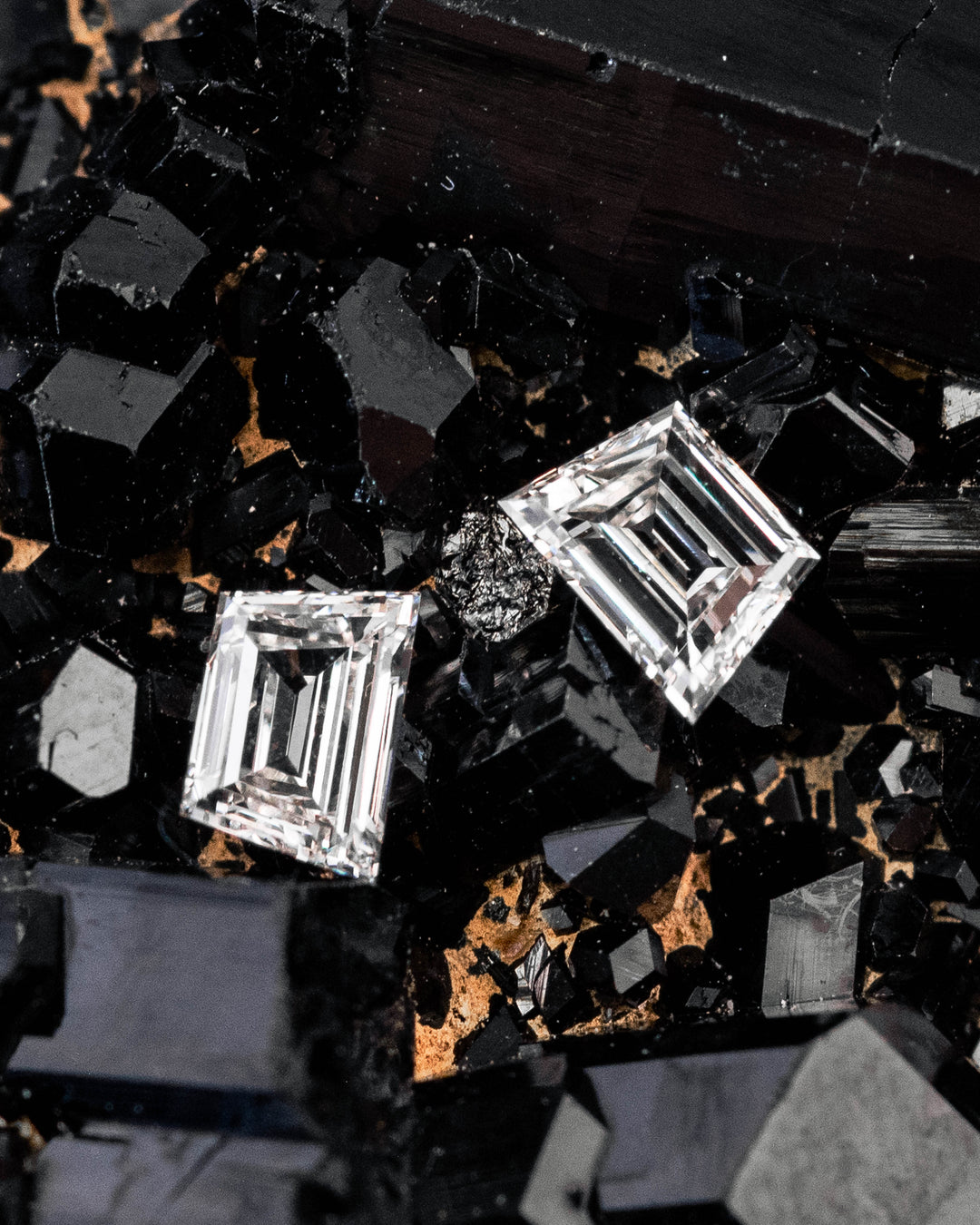 0.37-carat G-color VVS–VS trapezoid step cut diamonds resting on a black crystal mineral matrix, highlighting the geometric step faceting, brilliance, and natural untreated South African diamond pair.