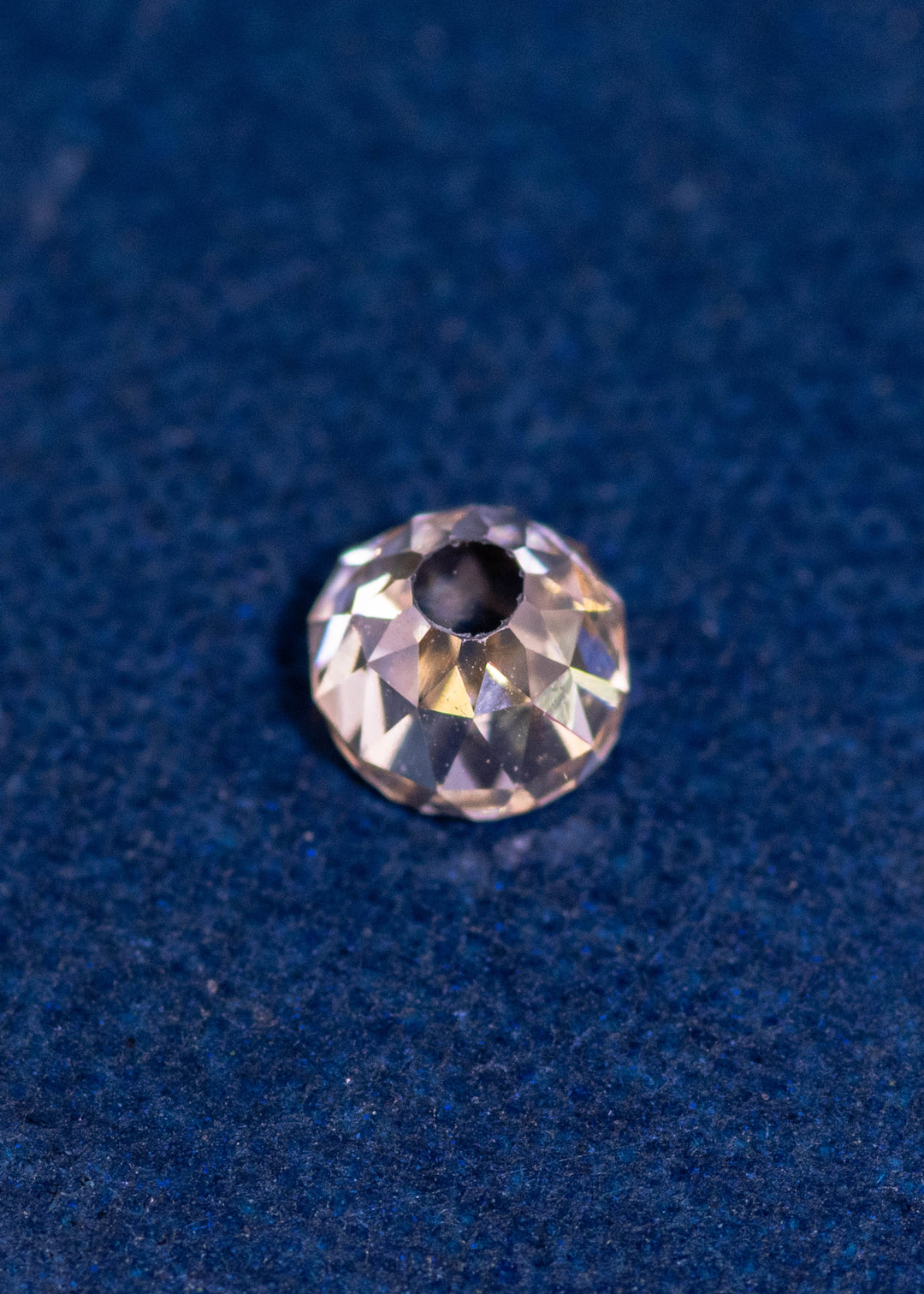 0.70-carat C4 fancy light brown rosy champagne diamond in Mughal cut resting on a blue textured surface, showing natural color and brilliance. VVS1 clarity diamond from South Africa photographed to display faceting and proportion.
