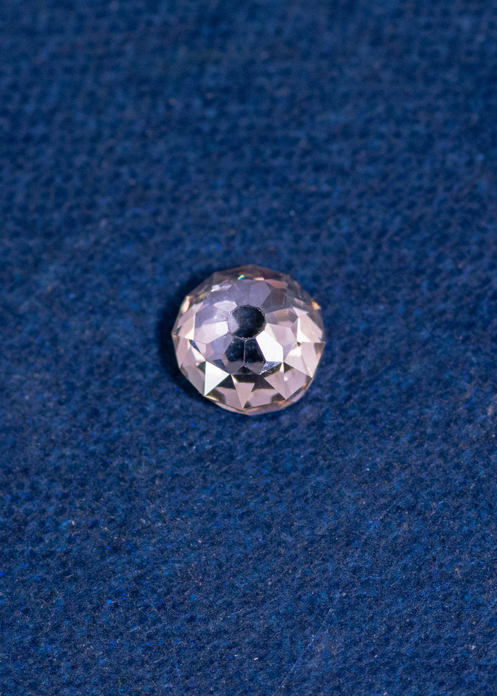 0.75 carat Mughal cut rosy champagne fancy light brown C4 diamond with VVS2 clarity resting on a blue surface, showcasing its faceting, transparency, and natural brilliance from South Africa.