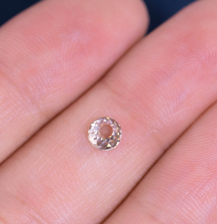 0.77 carat Fancy Light Brown C3–C4 Mughal cut diamond with VVS2 clarity resting on a fingertip to show size and brilliance; untreated natural diamond from South Africa with very strong blue fluorescence.