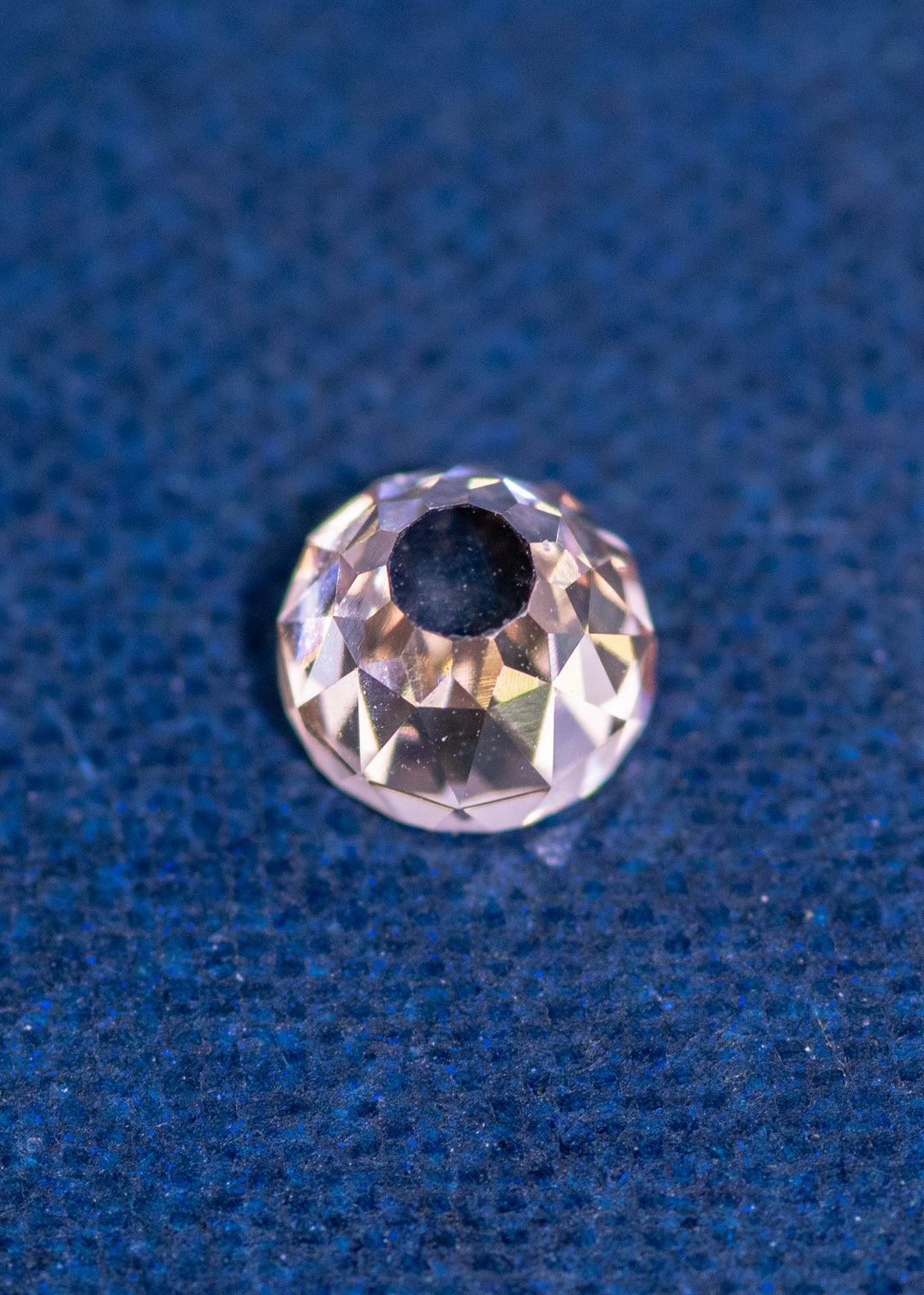 0.77 carat Fancy Light Brown C3–C4 Mughal cut diamond with VVS2 clarity and very strong blue fluorescence shown on a dark blue textured background, highlighting the concave faceting and round Mughal shape; natural diamond from South Africa, untreated.