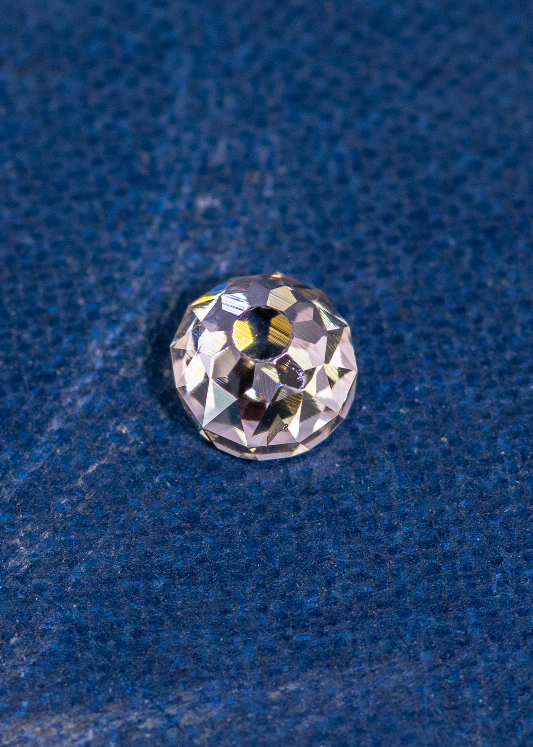 0.80 carat Fancy Light Brown C3 VVS2 Mughal Cut diamond from South Africa resting on a blue textured surface, showing intricate old-world facets and natural brilliance; untreated diamond with very strong blue fluorescence.