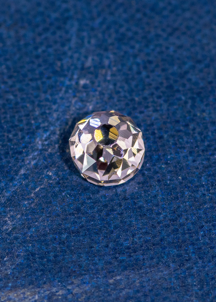 0.80 carat Fancy Light Brown C3 VVS2 Mughal Cut diamond from South Africa resting on a blue textured surface, showing intricate old-world facets and natural brilliance; untreated diamond with very strong blue fluorescence.
