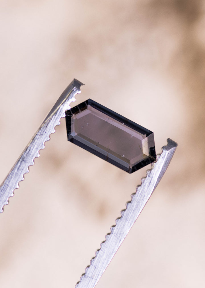 0.82ct pink purple Sri Lanka spinel held in tweezers, hexagonal step cut portrait displaying crisp step facets and natural violet undertones