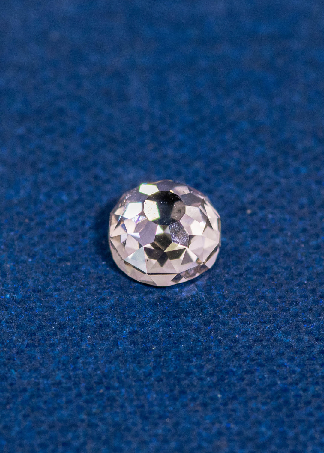 0.83ct Fancy Light Brown C2 VVS1 Mughal Cut Diamond from South Africa resting on blue textured background, showing antique-style faceting and high brilliance, untreated natural diamond.