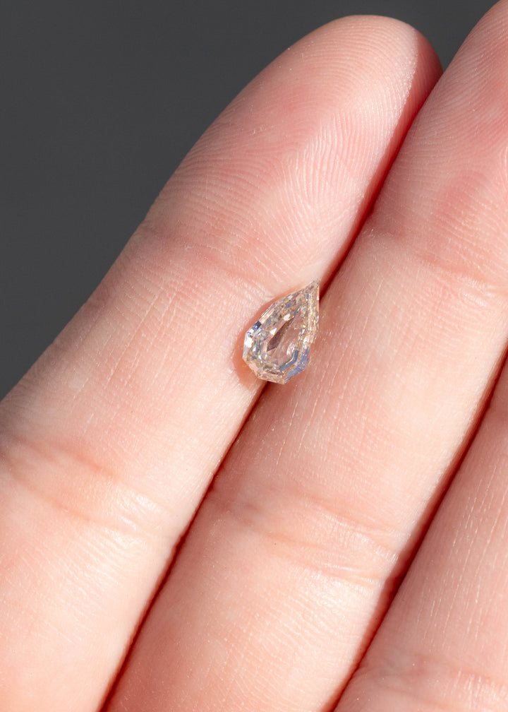 0.89ct Geo Pear Step Cut Champagne Diamond resting on fingertips under direct sunlight to show scale and color.