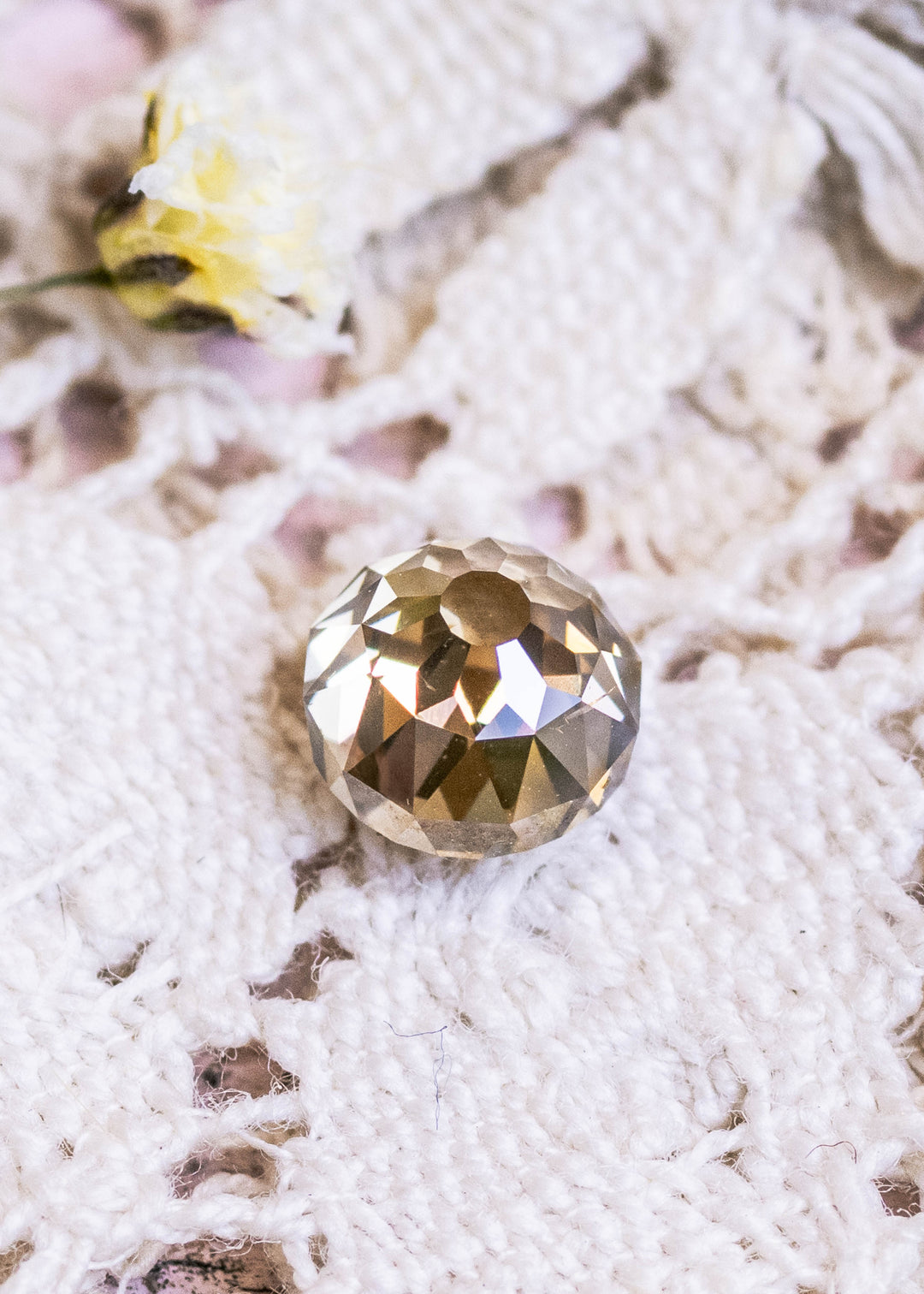 0.93ct champagne Mughal cut diamond resting on textured white fabric, showing warm fancy yellow brown tones and antique faceting.