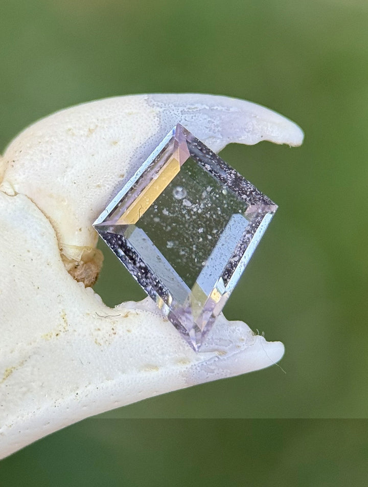 0.97ct untreated Colombian sapphire in pastel purple and pink, step cut kite shape shown in bright natural light.