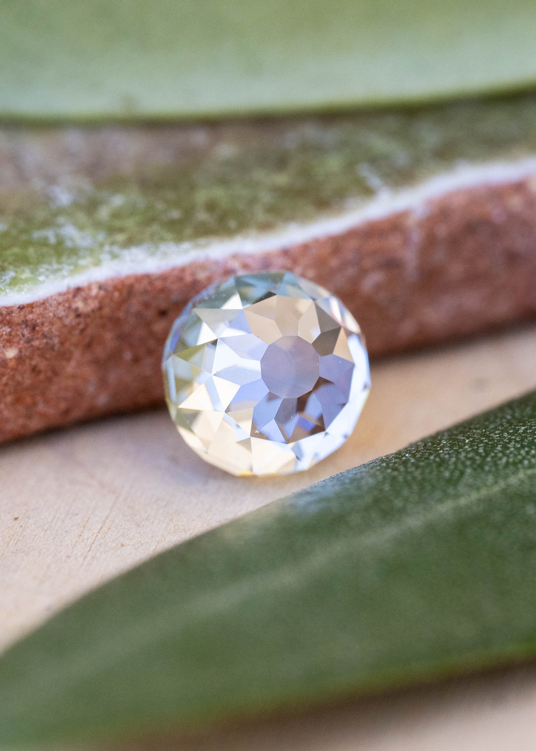0.99 carat round Mughal cut South African diamond resting between green leaves, showing its broad central table and softly irregular antique-style facets.