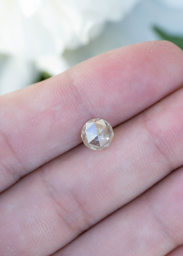 Natural 1.00 carat grey champagne rose cut diamond resting on fingertips for size comparison, showing its soft neutral champagne hue and antique-inspired faceting.