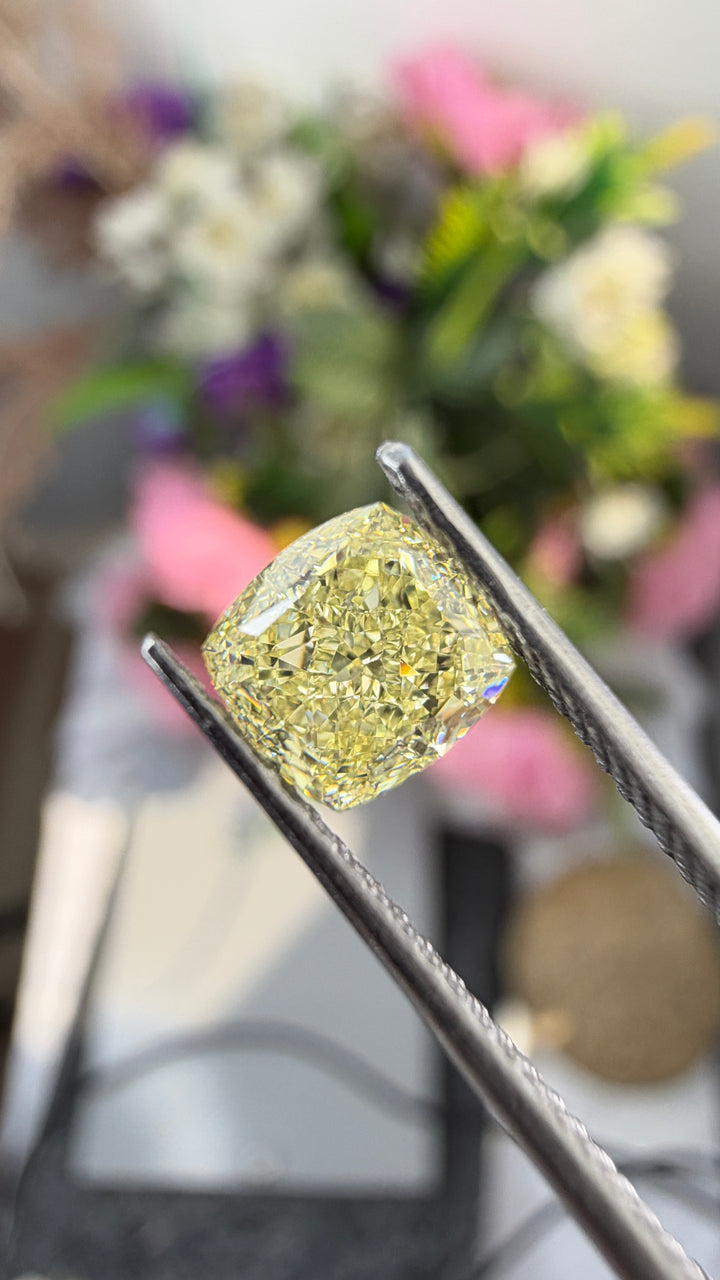 Close-up photography of a 1.00ct Fancy Light Yellow diamond highlighting its cushion-cut geometry and delicate yellow coloration.