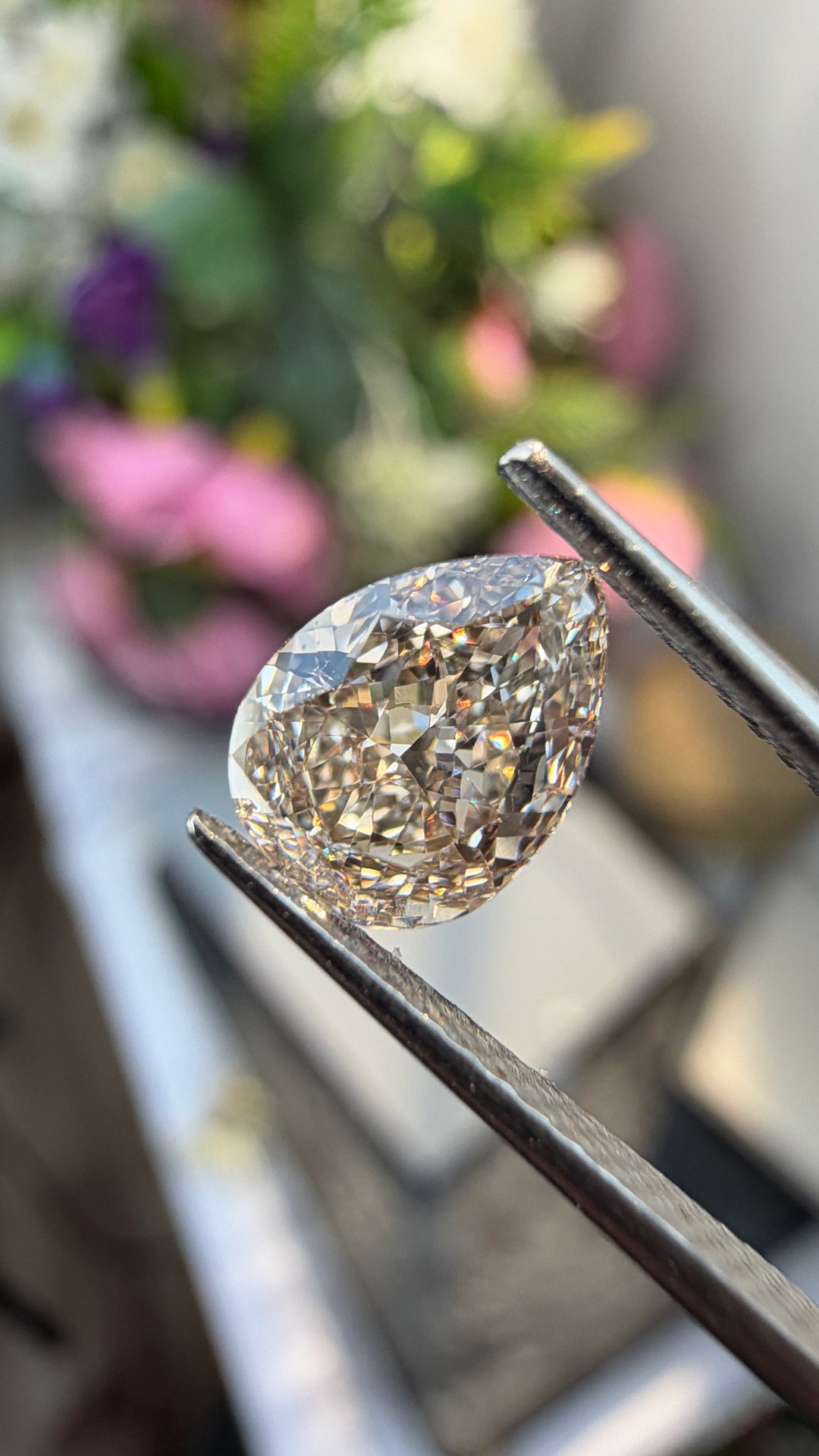 Detailed photograph of a 1.01ct Fancy Pinkish Brown diamond highlighting its pear-shaped outline, faceting and distinctive fancy color.