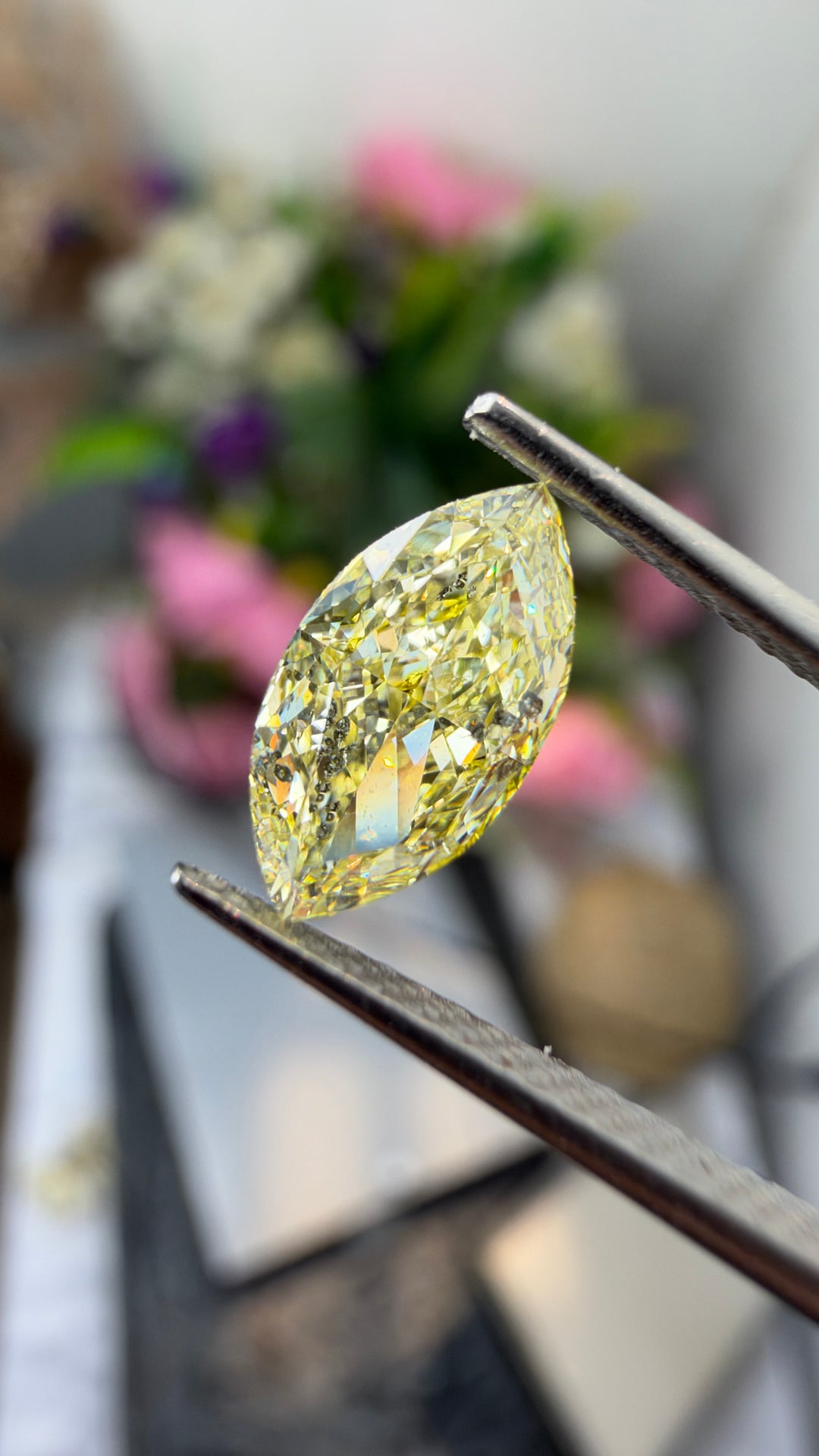 Close-up photography of a 1.03ct Fancy Yellow marquise diamond highlighting its elongated faceting, pointed silhouette and golden coloration.