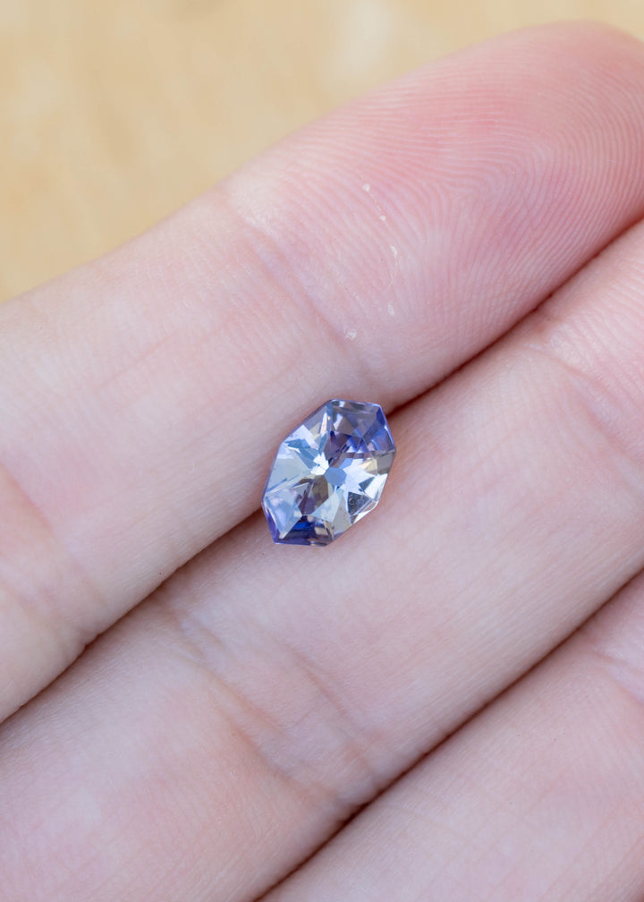 Natural 1.11 carat custom geometric marquise tanzanite displayed on fingertips, highlighting its elegant proportions and shifting purple blue coloration from Tanzania.