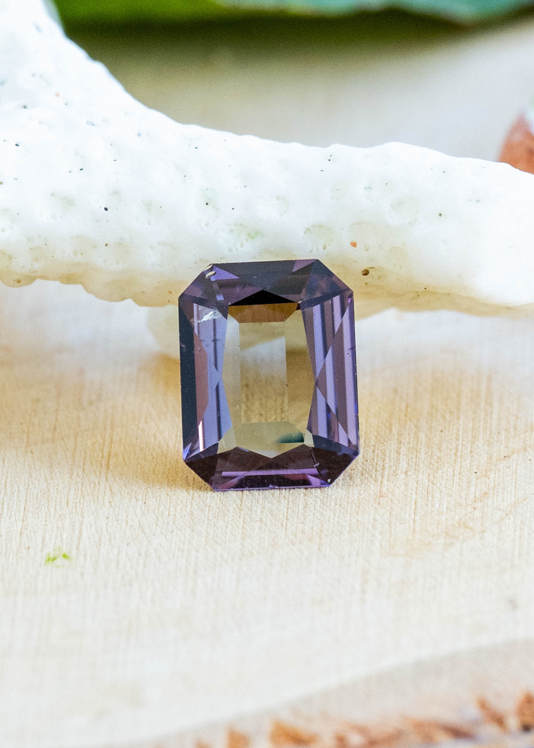 Natural 1.19 carat green and purple tanzanite from Merelani Hills, Tanzania featuring a custom radiant portrait cut displayed on white coral in natural light.