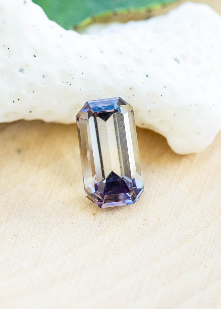 Natural 1.22 carat periwinkle purple tanzanite from Merelani Hills, Tanzania displayed on white coral, showcasing its elegant untreated emerald cut.