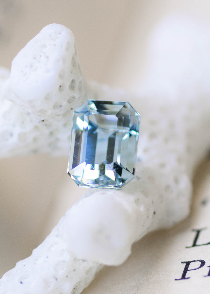 Untreated 1.45 carat baby blue Colorado aquamarine displayed on white coral, highlighting its custom octagonal step cut in natural daylight.