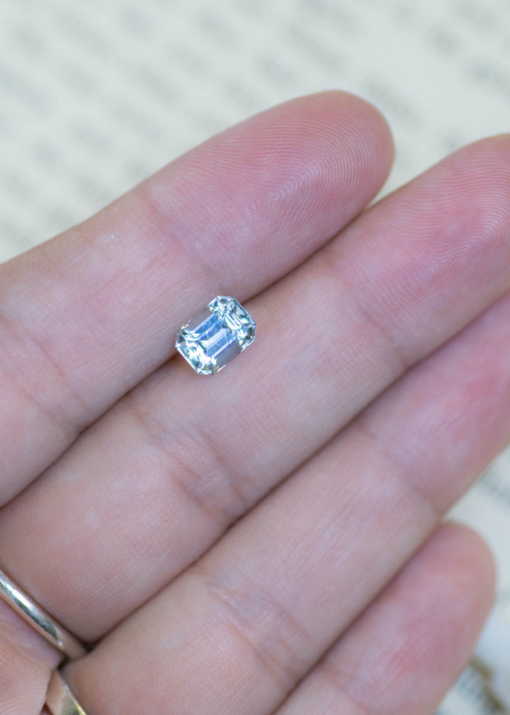 Natural baby blue Colorado aquamarine resting on fingertips, showing its custom octagonal step cut and face-up size.