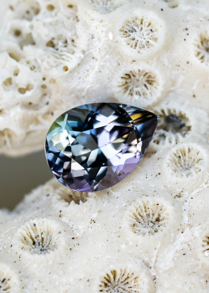 Natural 1.55 carat untreated Merelani Hills tanzanite featuring a modified mixed brilliant pear cut with blue, teal, green, purple, and golden color shifts.