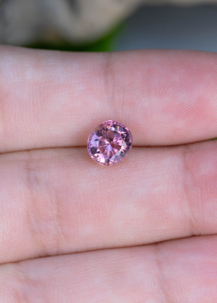 Natural 1.64 carat pink tourmaline displayed on the hand for scale, featuring an antique custom radiant round cut and bright rosy pink color.