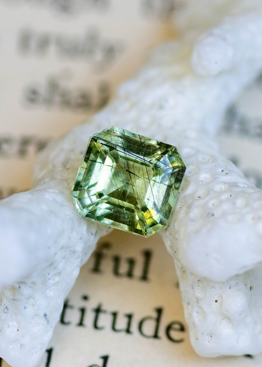 Natural untreated 1.72 carat lime green peridot from Pakistan displayed on white coral, featuring a precision custom Asscher cut and natural crystal inclusions.