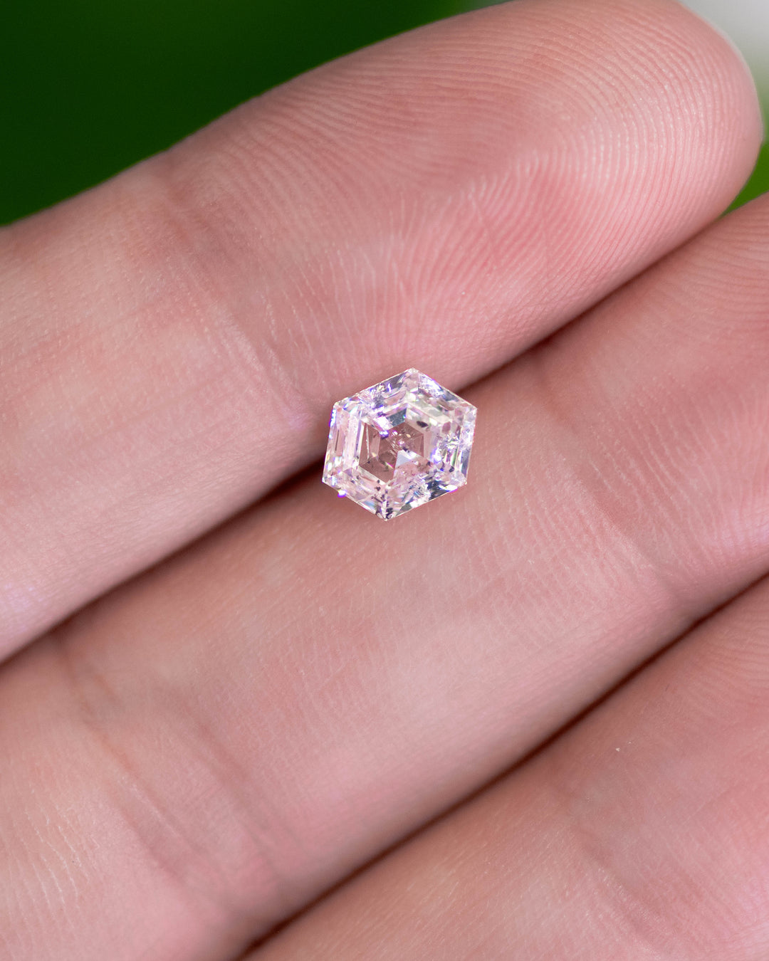1.01 carat G color I2 clarity hexagonal step cut diamond resting on a fingertip, displaying clarity characteristics and high-quality cutting symmetry. Natural untreated diamond sourced from Gahcho Kué, Canada.