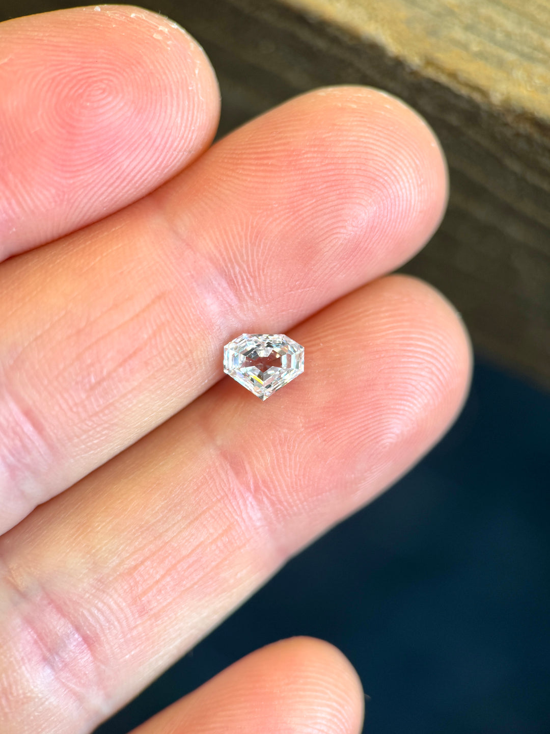 1.01 carat shield step cut E color SI1 clarity diamond displayed on a fingertip to highlight its proportions and clarity. Natural untreated diamond ethically sourced from Gahcho Kué, Canada.
