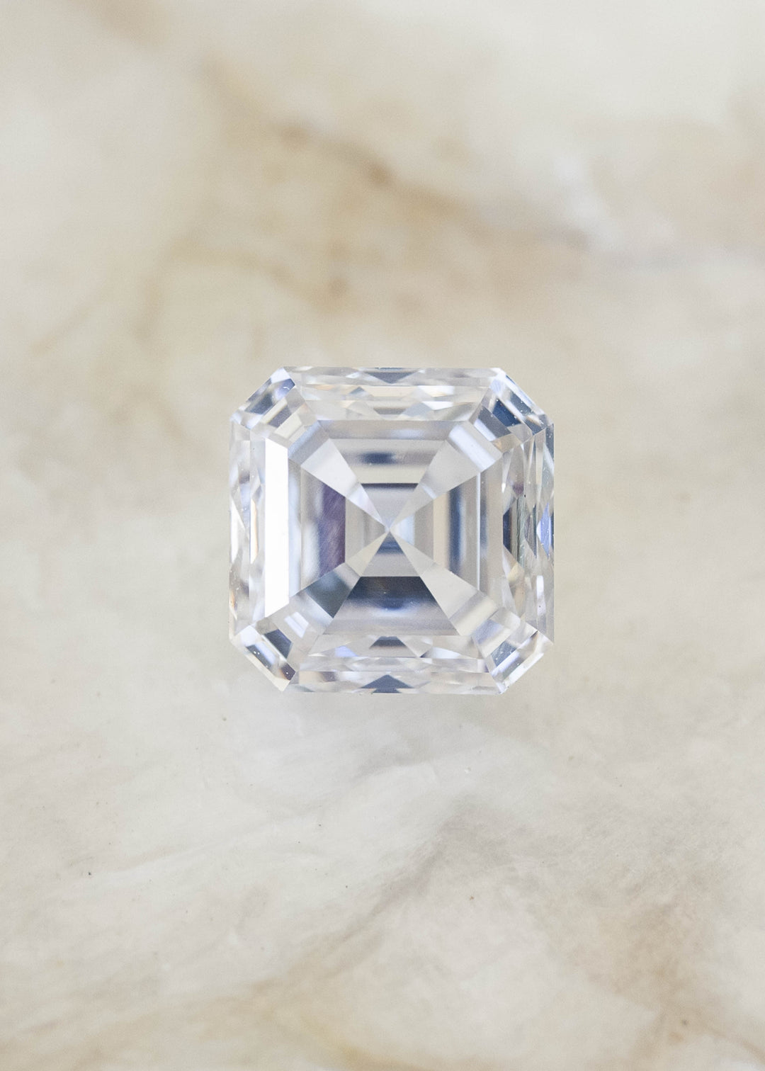 Face-up 1.01 carat natural Asscher cut diamond on a pale background, displaying a nearly square outline, warm ivory tone and concentric geometric facets.