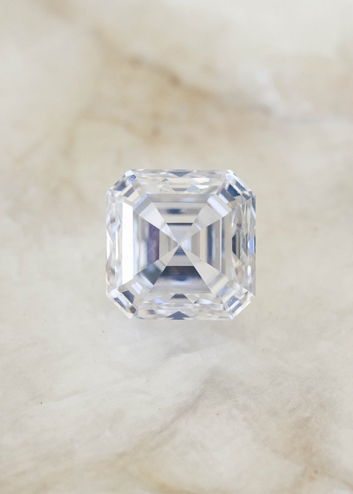 Face-up 1.01 carat natural Asscher cut diamond on a pale background, displaying a nearly square outline, warm ivory tone and concentric geometric facets.