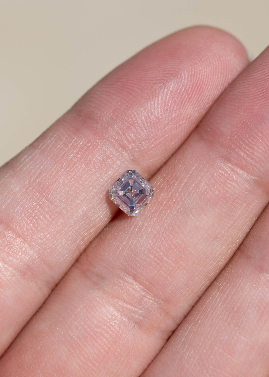 1.01 carat M color VVS1 Asscher cut diamond resting on a hand for scale, with geometric reflections visible through its exceptionally clean step-cut interior.