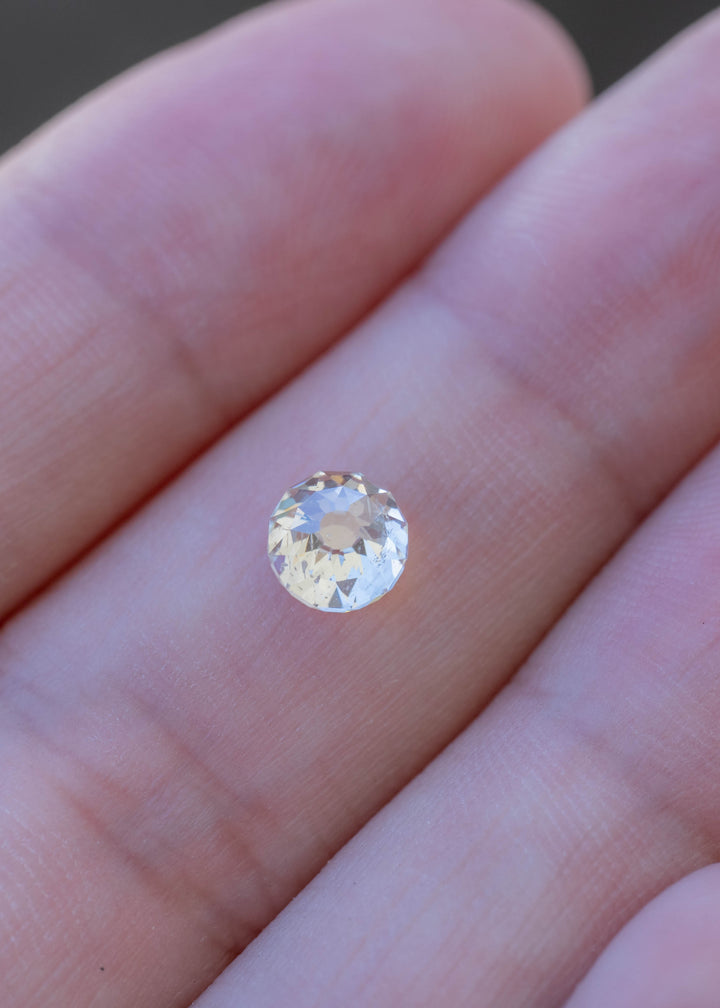 1.01 carat round Mughal cut diamond resting on a fingertip for scale, with natural inclusions and broad flashes visible through its radial facets.