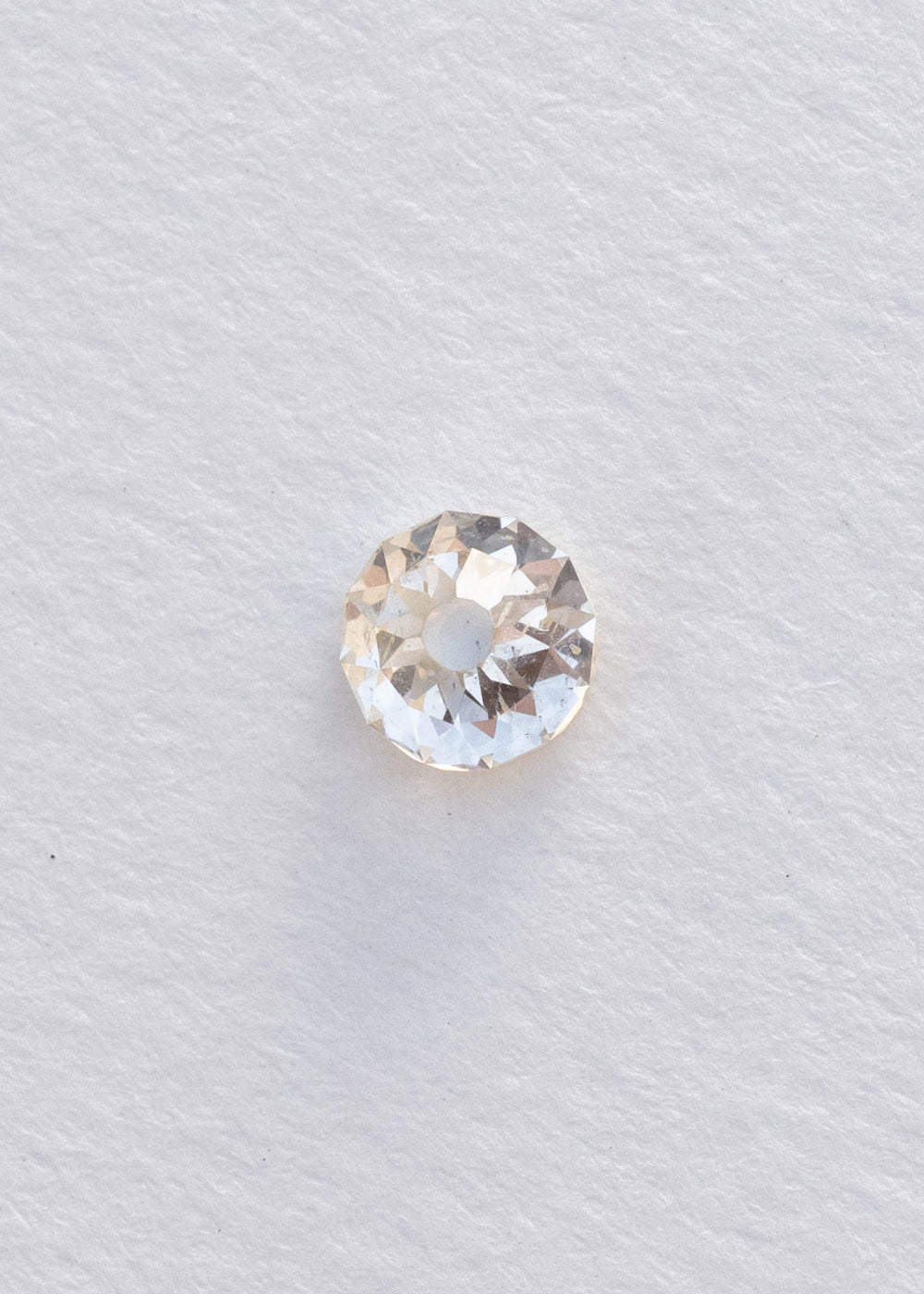 Face-up South African Mughal cut diamond on a white background, clearly showing its nearly round outline, circular central table, irregular radial facets and natural inclusions.