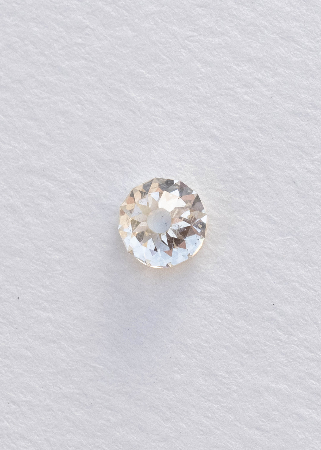 Face-up South African Mughal cut diamond on a white background, clearly showing its nearly round outline, circular central table, irregular radial facets and natural inclusions.