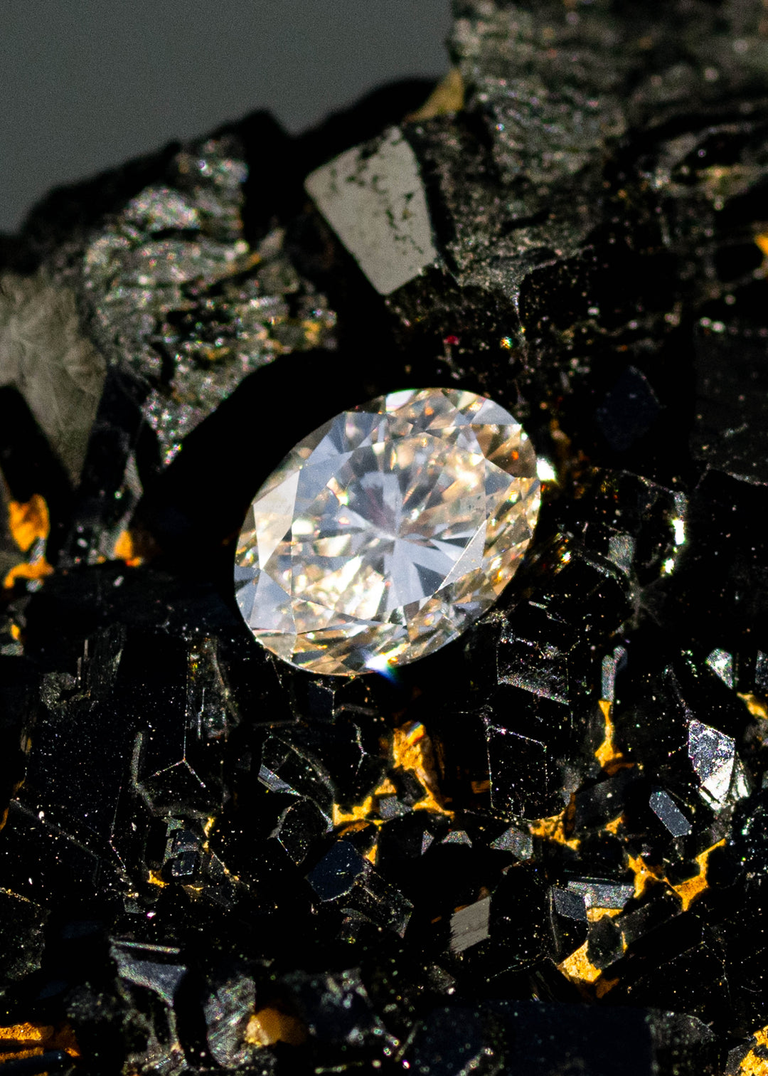 1.01ct champagne c3 oval brilliant cut diamond resting on natural tourmaline gemstone under direct sunlight.