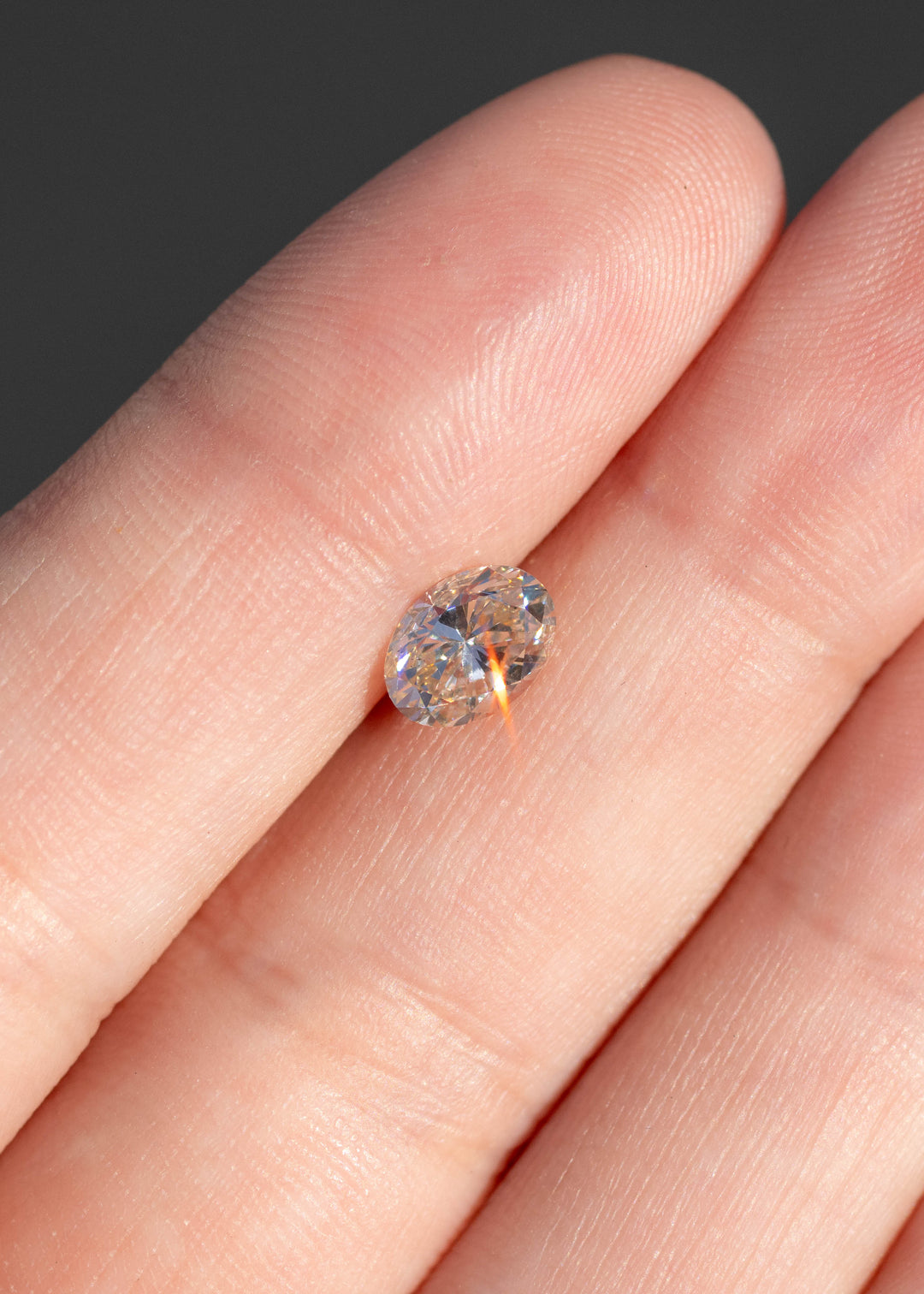 1.01ct champagne c3 oval brilliant cut diamond resting in hand showing off natural color and brilliant sparkle.