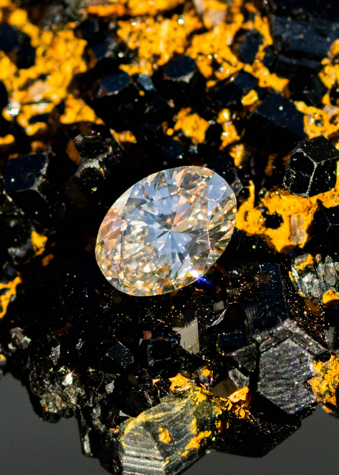 1.02ct natural champagne oval brilliant cut diamond from Canada resting on natural black tourmaline matrix in direct sunlight.