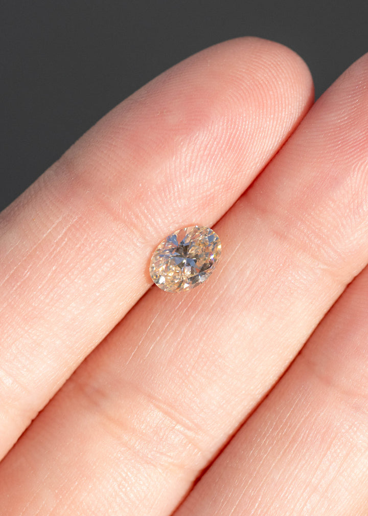 1.02ct natural champagne oval brilliant cut diamond from Canada held in hands under direct sunlight.