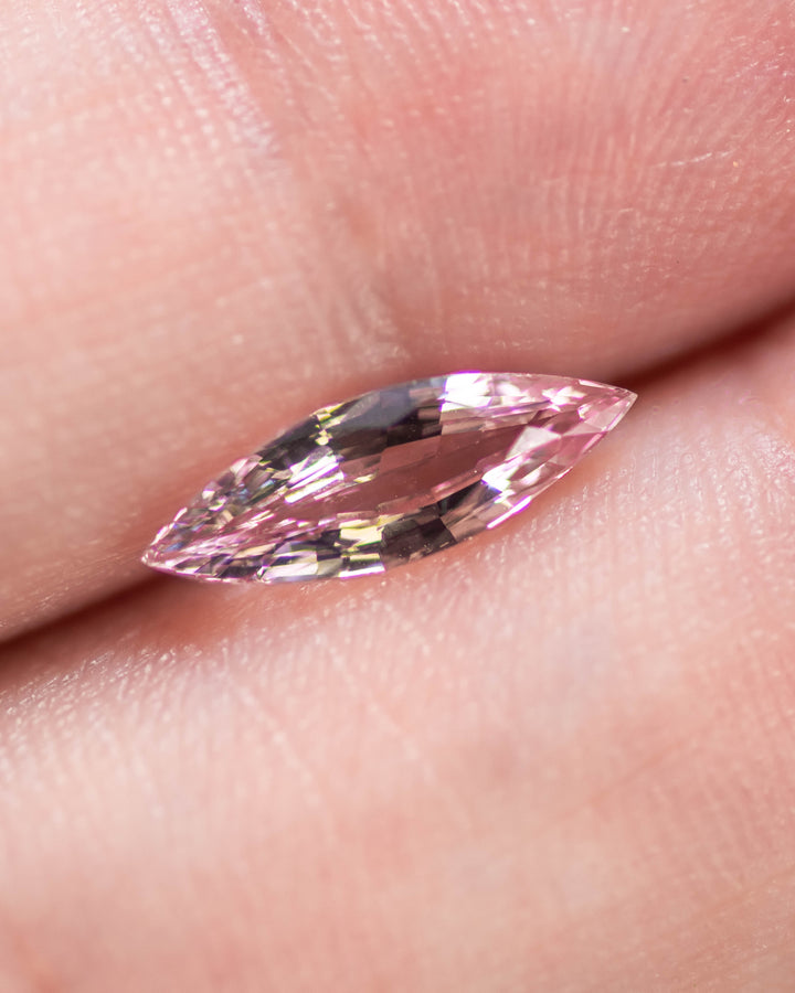 1.03 carat blush pink sapphire displayed on fingertip, revealing soft rosy hues, clarity, and fine craftsmanship of the precision marquise mixed cut, heated sapphire from Sakaraha, Madagascar.