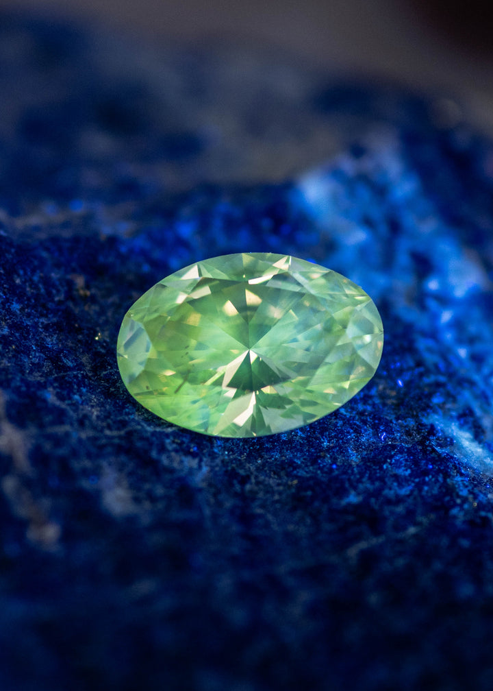Oval diamond under UV light displaying rare green fluorescence, natural fluorescent diamond gemstone.