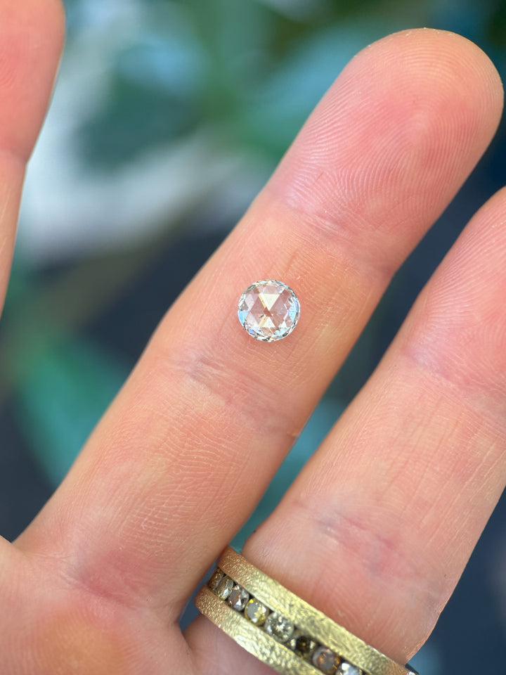 1.04 carat diamond balanced on fingertip for size comparison, featuring a round rose cut with soft vintage faceting and clean white F color, ethically mined and untreated from Gahcho Kué Mine, Canada.
